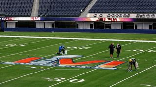 Workers paint logos on the field in preparation for Super Bowl LVI at SoFi Stadium