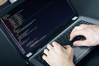Man typing code on a laptop