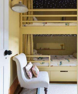 Yellow painted kids' room ideas with built-in bunk beds and a pale gray chair.