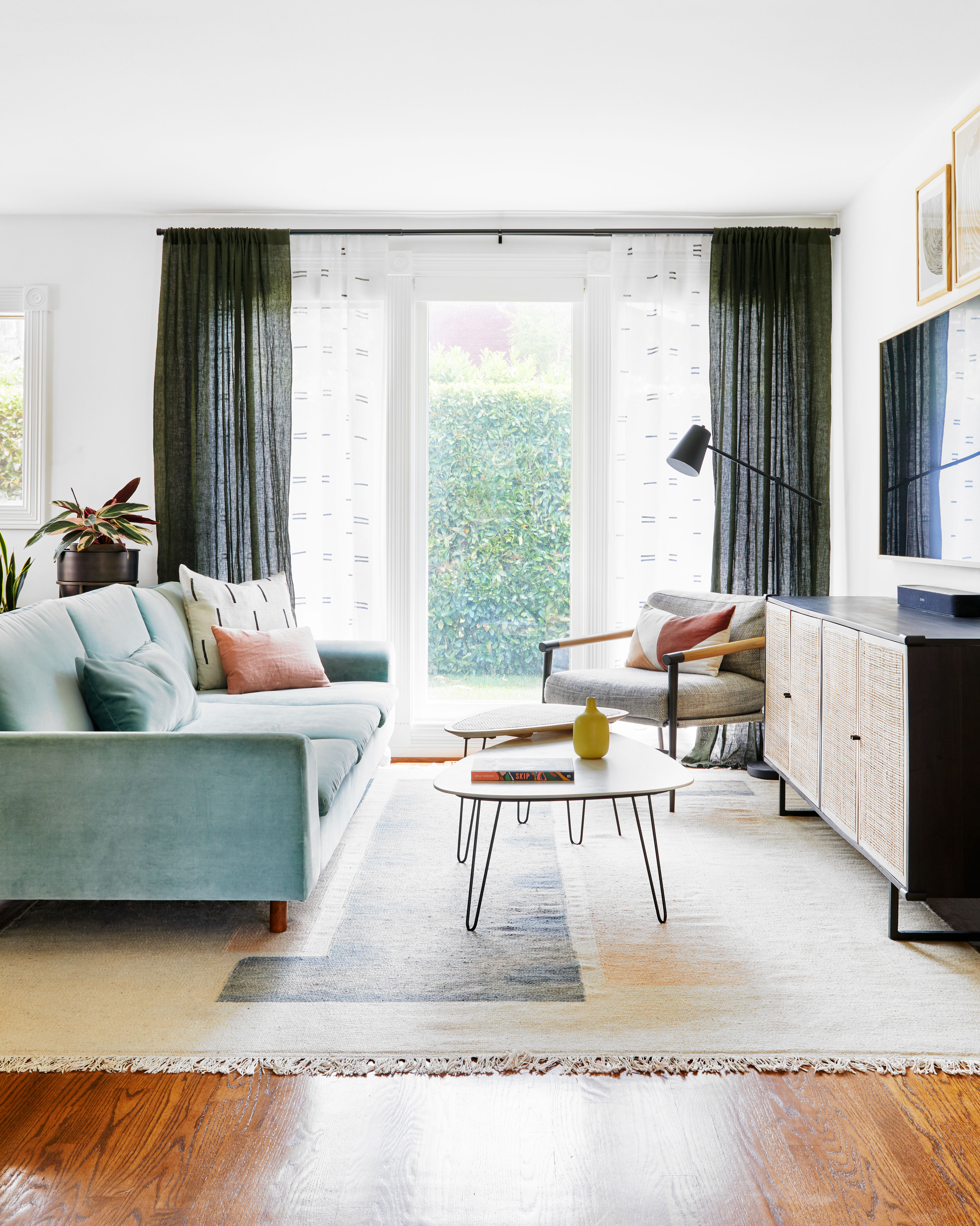 White living room with light blue sofa and green curtains