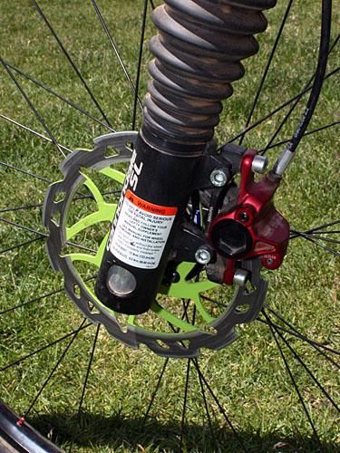 The front brake caliper clamps down on a lightweight metal matrix rotor from Scrub Components.