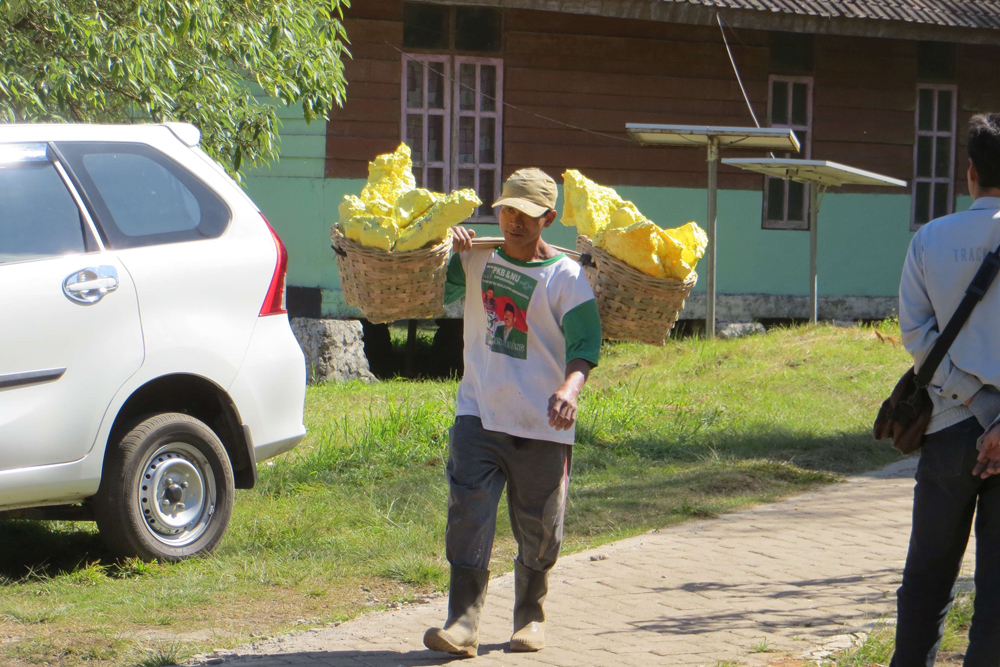 A sulfur miner carries 150 lbs. of the yellow mineral down from Ijen Crater dome.