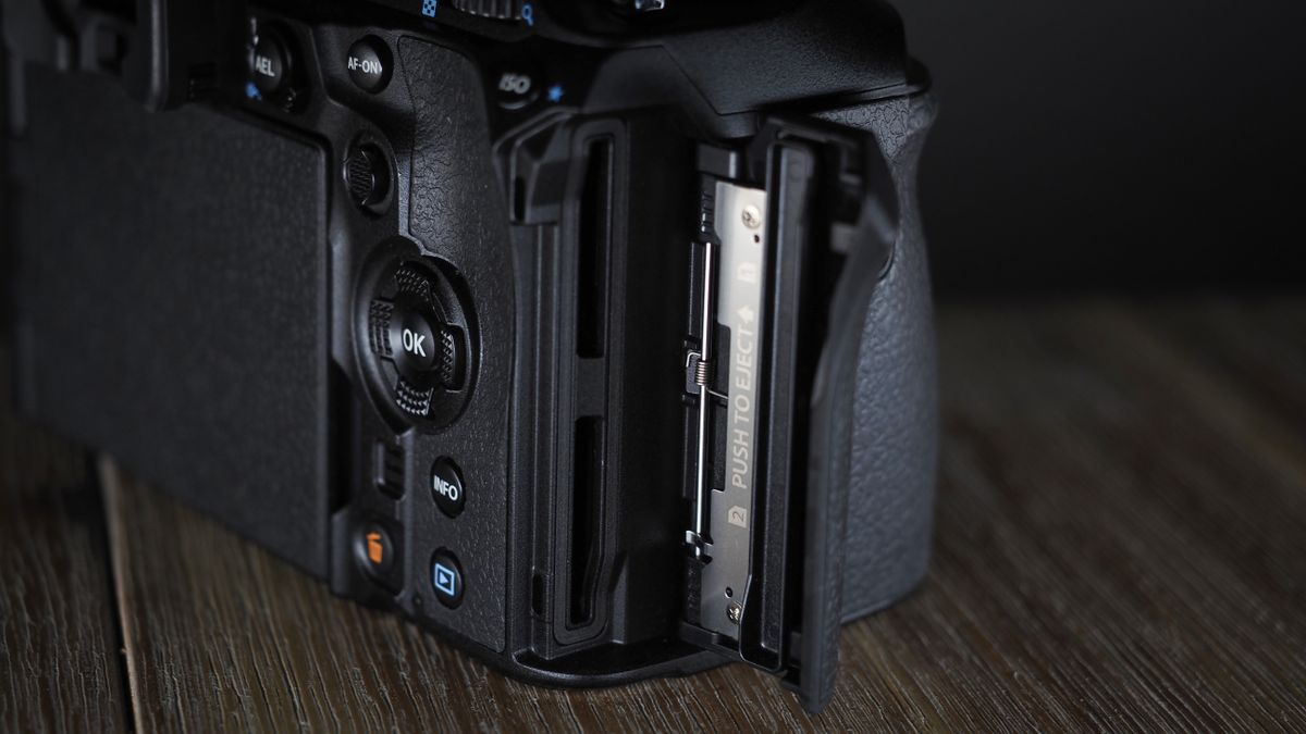 OM System OM-1 Mark II on a wooden surface, against a dark background