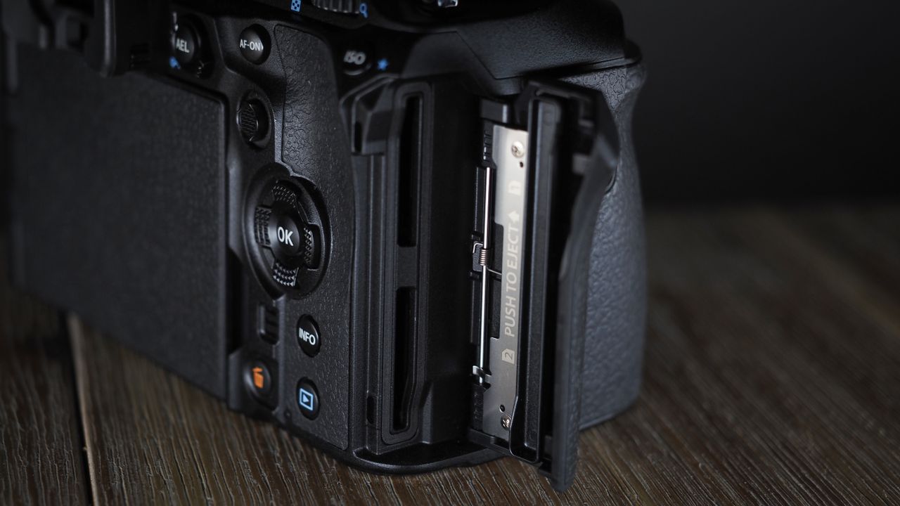 OM System OM-1 Mark II on a wooden surface, against a dark background