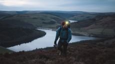 Man wearing special hiking clothes on dark mountain with head torch