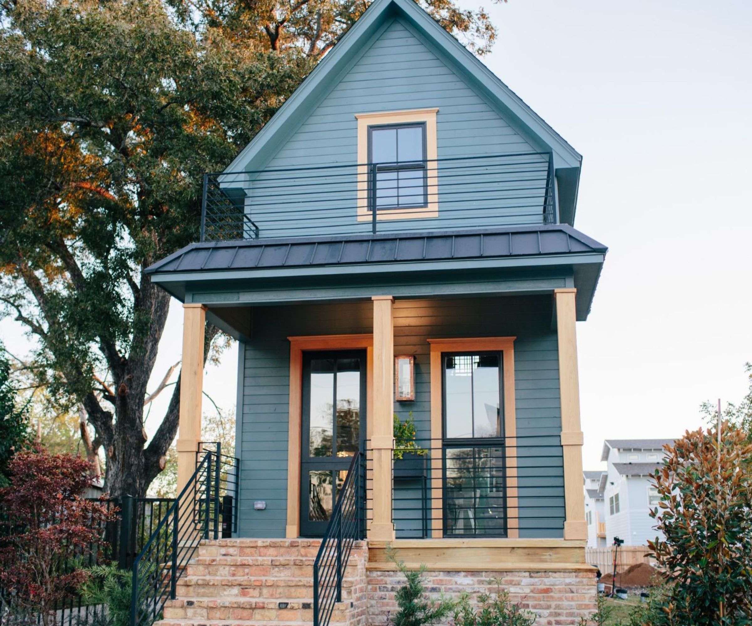 Shotgun house exterior with blue and wood facade and brick steps