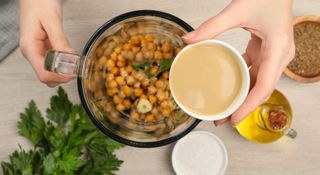 Chickpeas being mixed with tahini in a blender