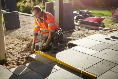 Workman laying a patio in slate