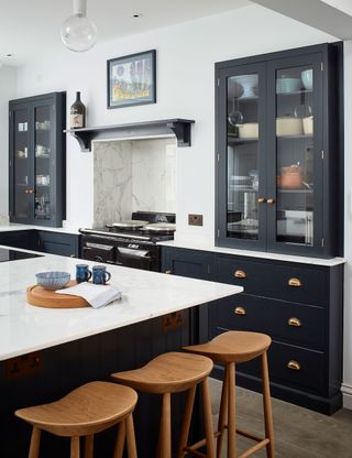 Gray and white kitchen with marble countertop, wood stools and flooring