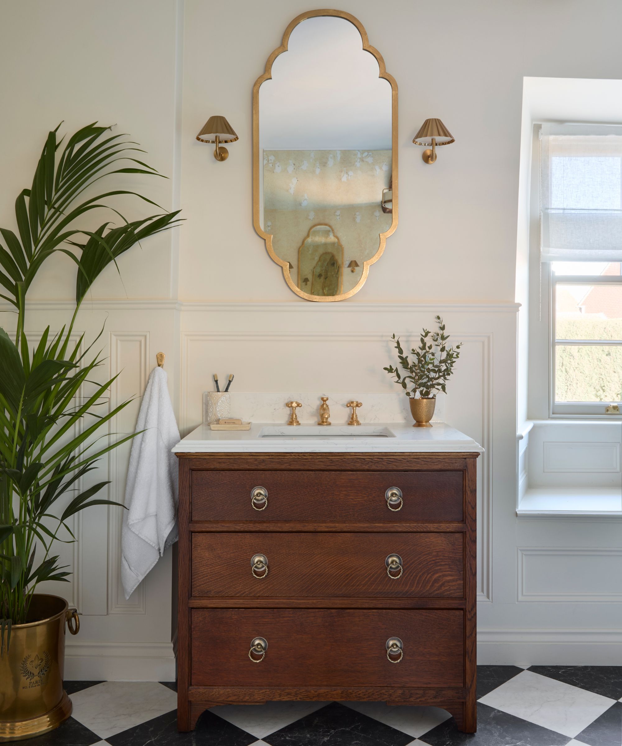 A small bathroom vanity created by upcycling an old wooden chest of drawers and adding a marble top