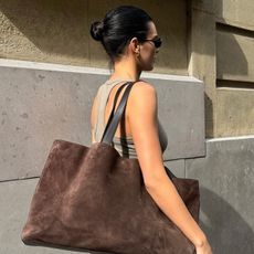 Kendall jenner wears a taupe tank top and brown suede tote bag.