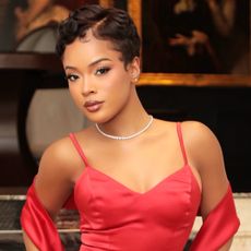 Actress Maleah Joi Moon wears a red gown and shawl while posing in a museum at Netflix's 'A Different World' premiere.