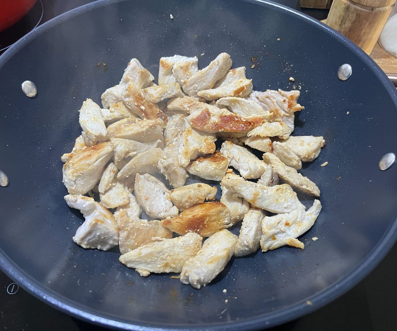 Chicken browning in a blue ceramic wok