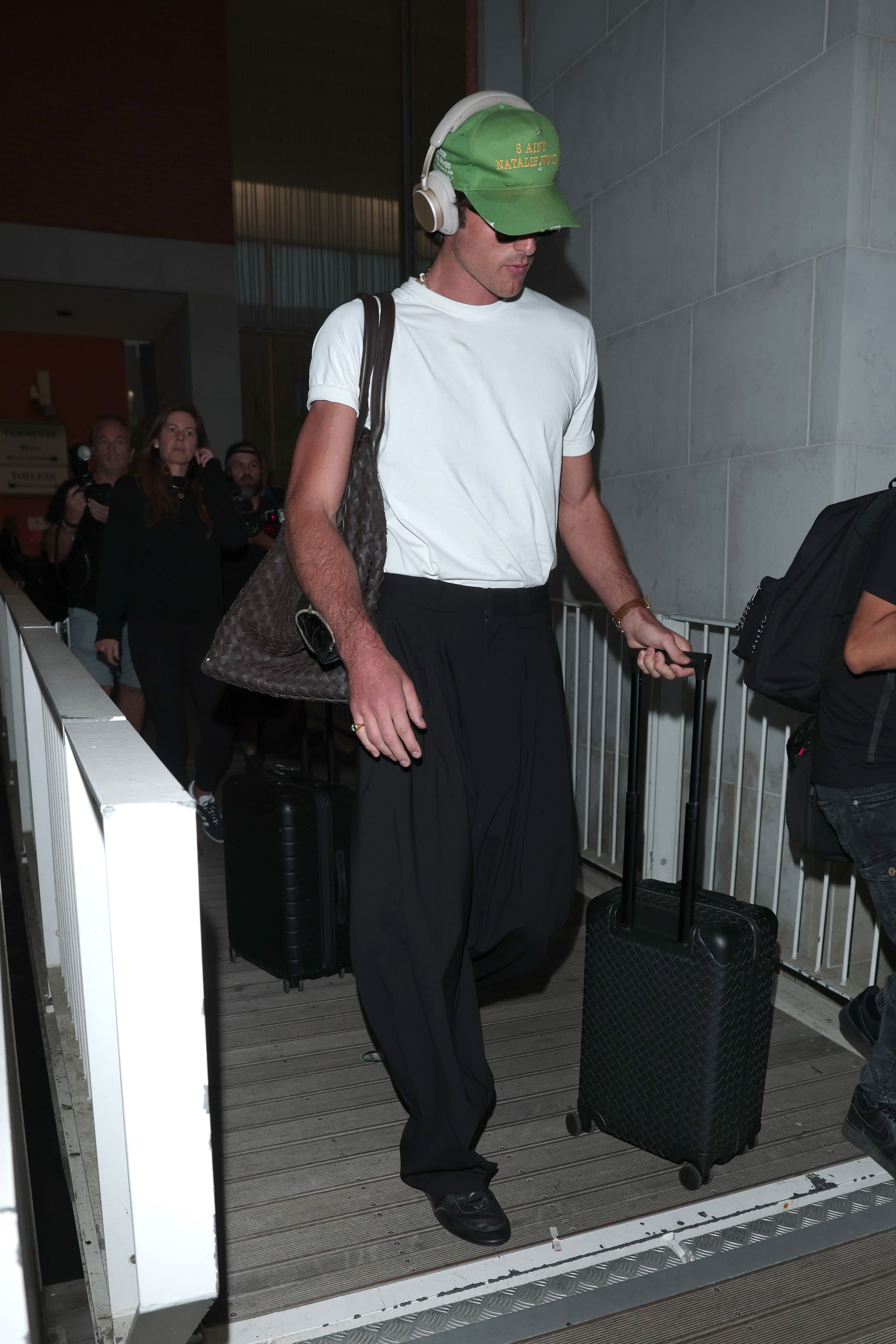 Jacob Elordi wears a white t-shirt with jeans and black trousers.
