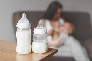 Breast milk bottles in front of woman breast-feeding.