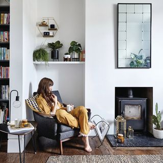 living room with white wall girl seating on chair and wooden flooring