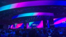 Andy Jassy, President and CEO at Amazon, onstage at the opening keynote for AWS re:Invent 2024. The picture has been taken in wide angle, and the stage is covered in screens showing blue, pink, and purple gradients.