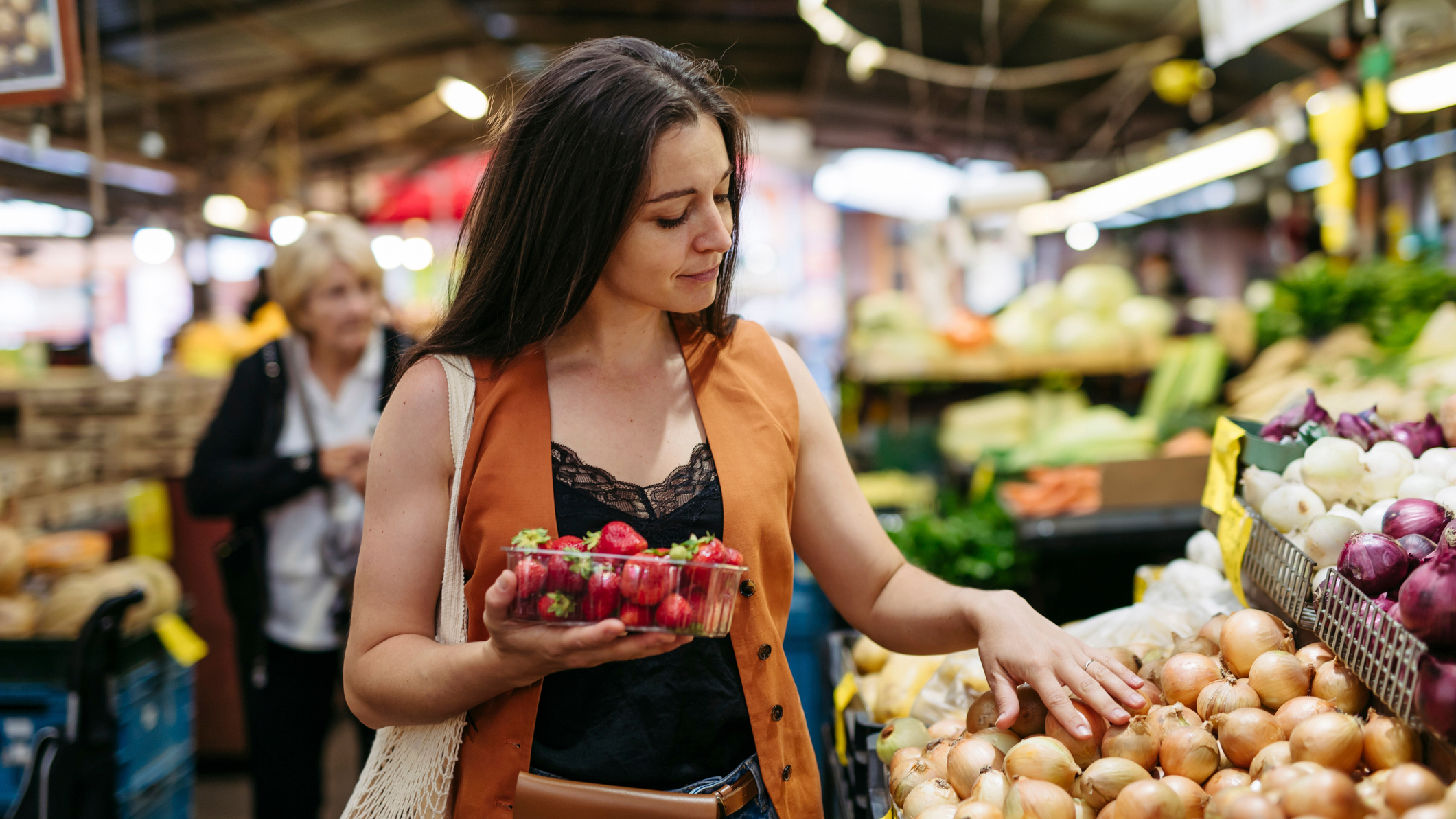 Woman in grocery store holding a plastic punnet of strawberries