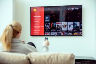 woman sat on sofa watching catch up tv online