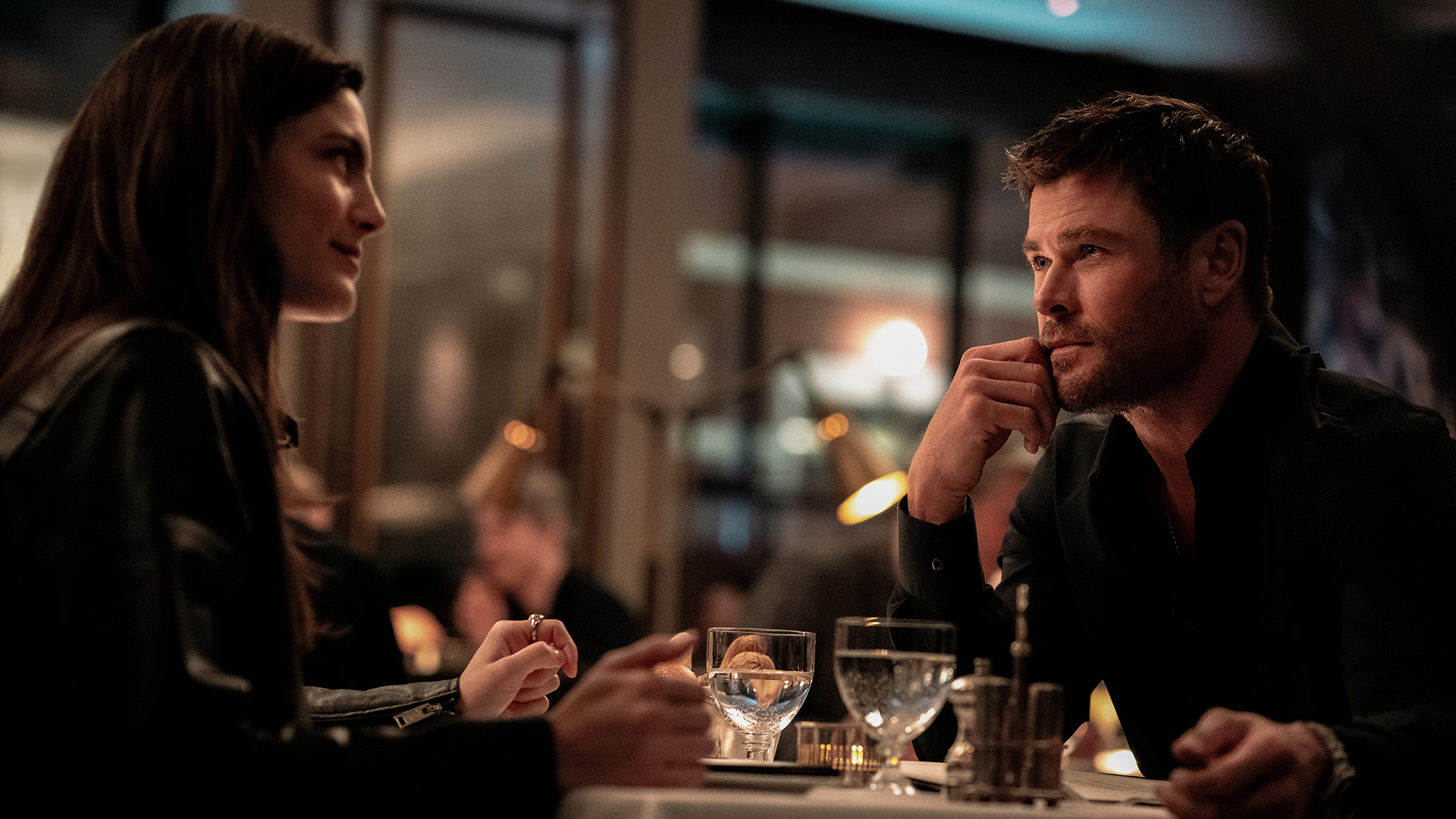 Maya sitting opposite Davis on a night-time date in Crime 101