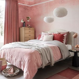 pink wall bedroom with grey flooring and white bed with pink cushion