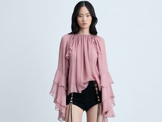 model wears pink blouse, black shorts, and tall boots