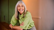 Happy mature woman smiling while leaning on table 