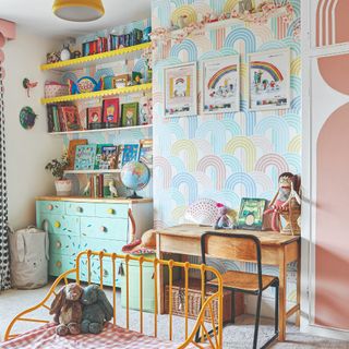 A kids' room with a rainbow wallpaper and desk and lots of toy storage