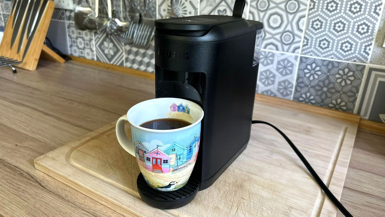 Keurig K-Mini Mate coffee maker on kitchen counter dispensing coffee into larger mug
