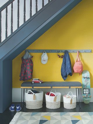 understairs storage for kids, coats, bags and shoes with bench and yellow pegboard wall