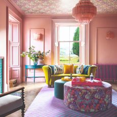 A pink-painted living room with sheen on the walls and a ceiling covered in a floral wallpaper