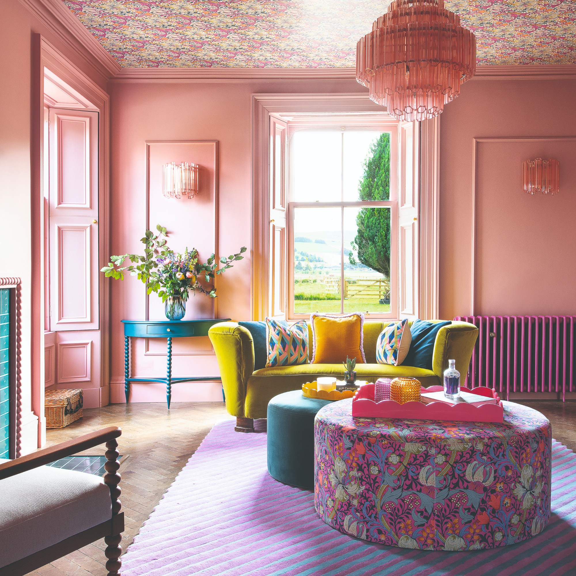 A pink-painted living room with sheen on the walls and a ceiling covered in a floral wallpaper