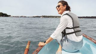 Are Fitbits waterproof: Woman sitting in canoe wearing Fitbit Sense