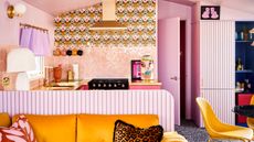 Fun, quirky, multifunctioning small space featuring pink and yellow hues, retro patterned wall paper, paneled finishes, and honeycomb glazed backsplash wall tiles.
