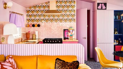 Fun, quirky, multifunctioning small space featuring pink and yellow hues, retro patterned wall paper, paneled finishes, and honeycomb glazed backsplash wall tiles.
