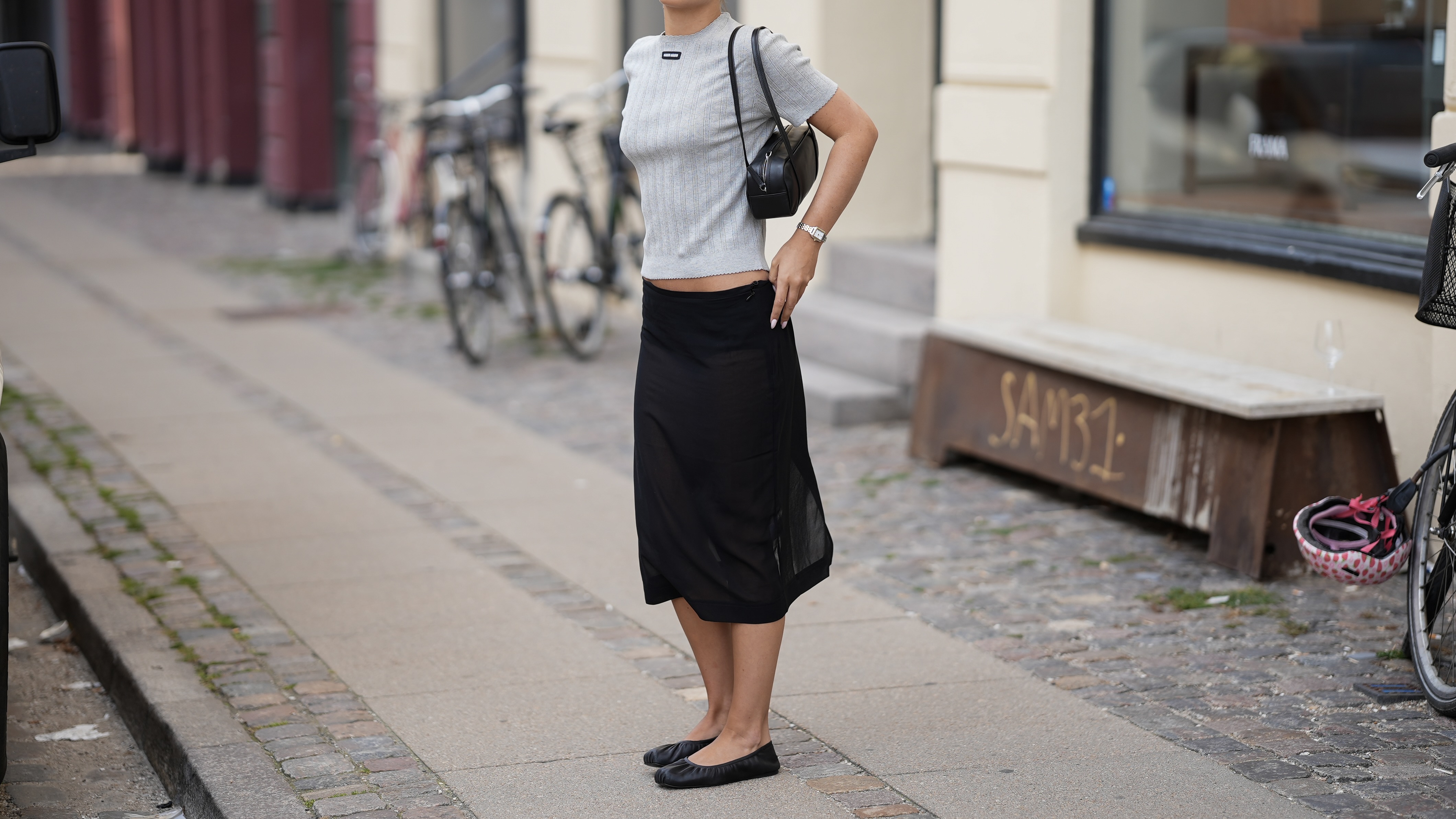 woman wearing a gray miu miu tshirt and black midi skirt with black flats