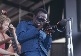 American trumpeter and composer Miles Davis (1926 - 1991) performing at the Newport Jazz Festival at Newport, Rhode Island, 4th July 1969. On the left is Dave Holland on bass