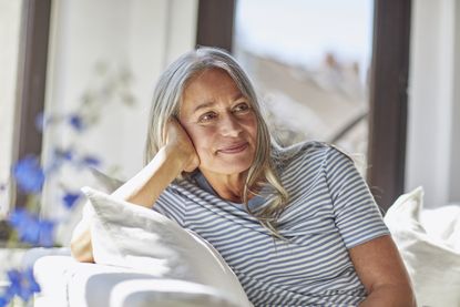 Average age of menopause: Smiling woman relaxing on sofa in living room