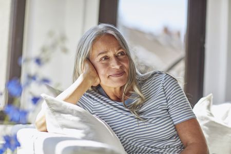 Average age of menopause: Smiling woman relaxing on sofa in living room