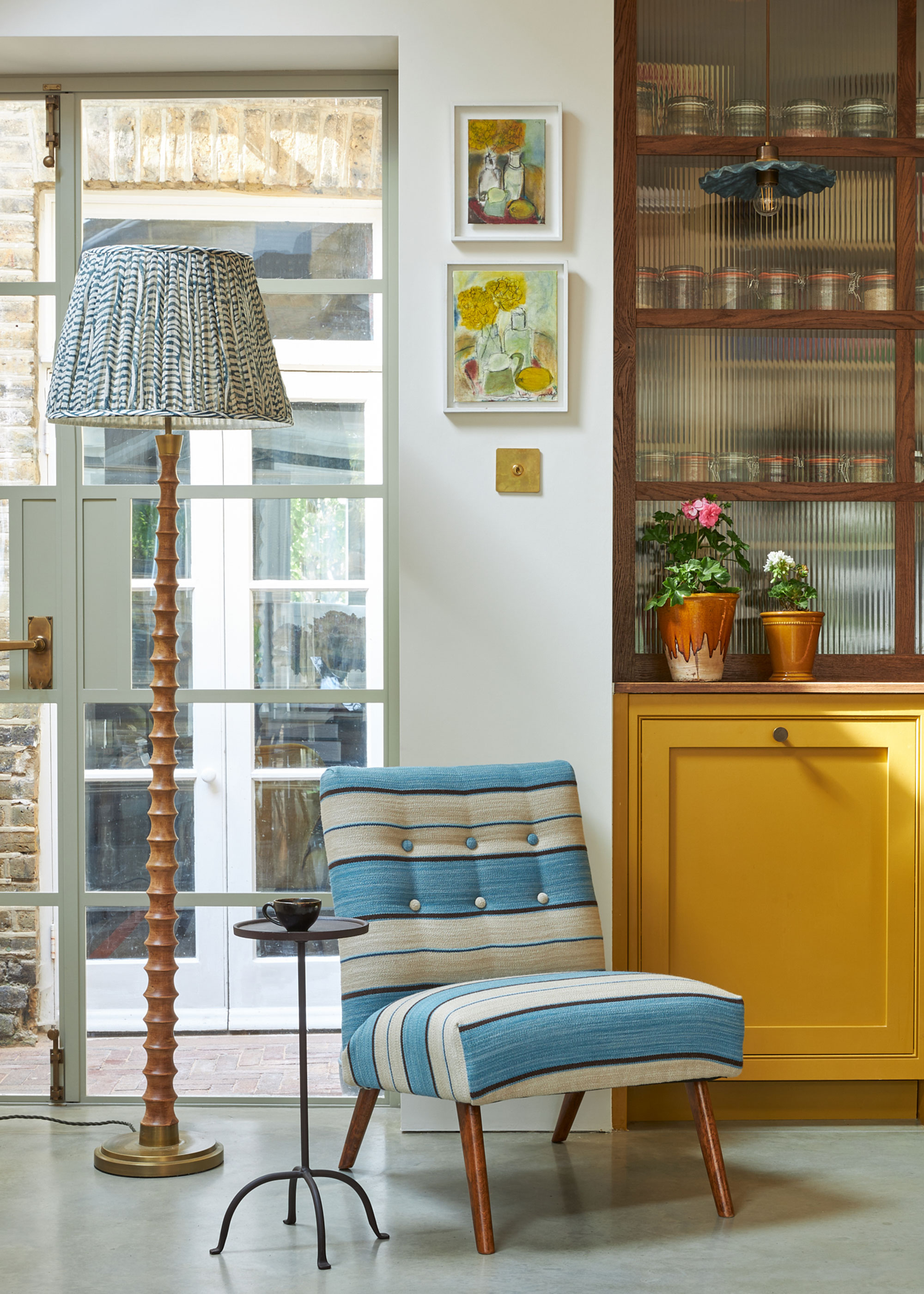 reading corner with floor lamp with wooden base and blue and white shade with blue and white chair and yellow dresser