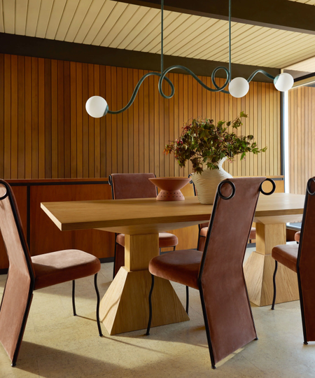 a whimsical dining room with a curved chandelier and playful dining chairs