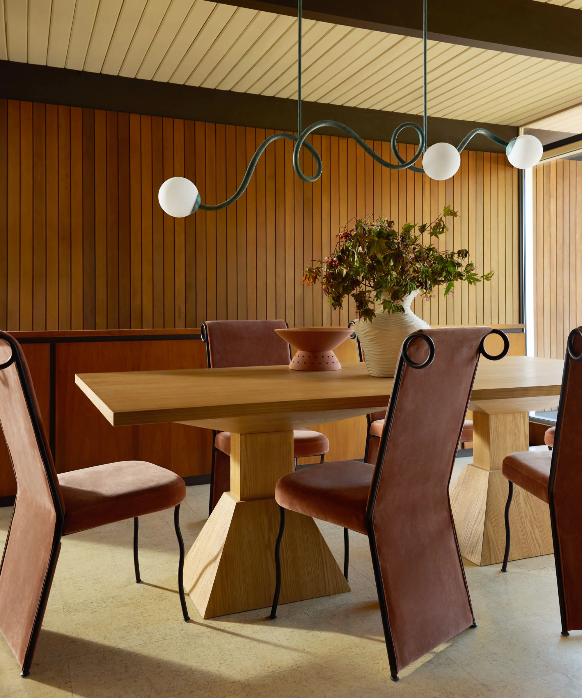a whimsical dining room with a curved chandelier and playful dining chairs