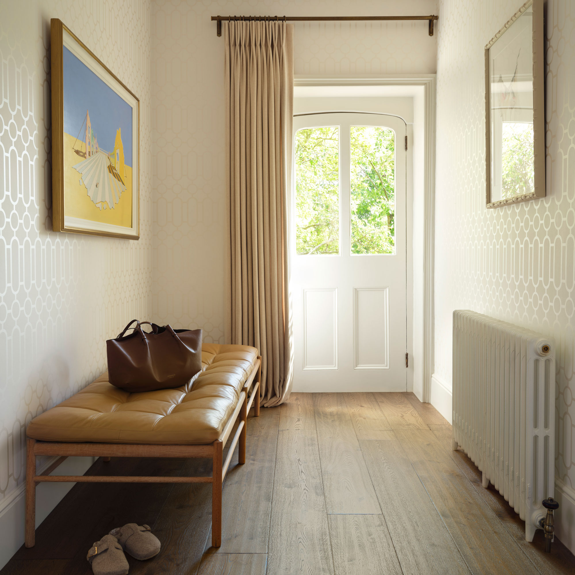 hallway with wide plank wooden flooring and period front door and white column radiator