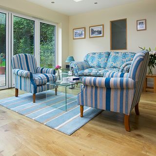 living room with cream colour wall blue and white designed sofa frames on wall and wooden floor