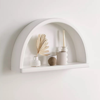 A white semicircle wall shelf with boho accessories
