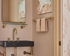 A neutral powder room with bronze detailing and artwork
