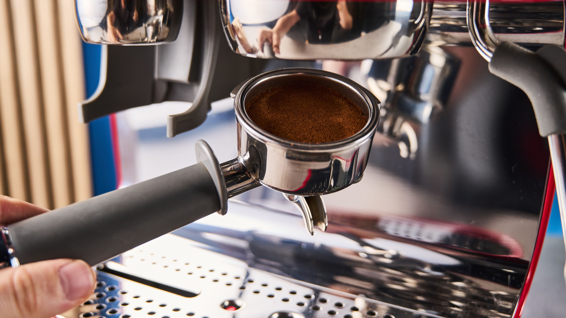 a red smeg espresso machine with burr grinder is photographed against a blue background
