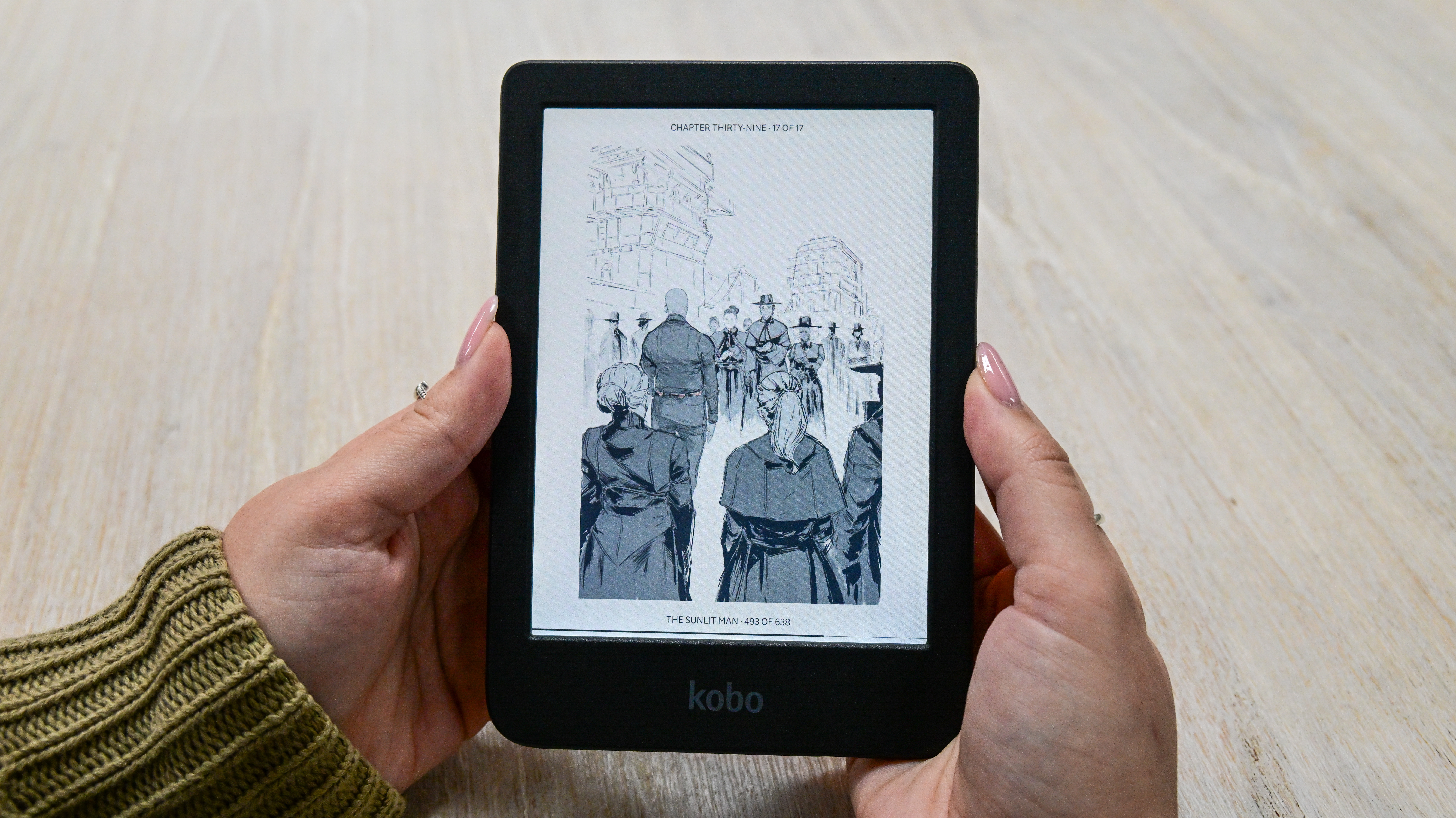 A person holding the Kobo Clara Colour ereader displaying an illustration