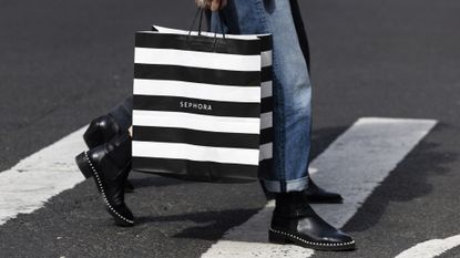A pedestrian carries a Sephora shopping bag in the SoHo neighborhood of New York, US on Wednesday, March 22, 2023. US retail sales fell in February after a surge in the prior month, suggesting consumer spending, while holding up, is getting challenged by high inflation.