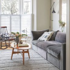 Beige painted living room with a grey sofa and a wooden coffee table in front it